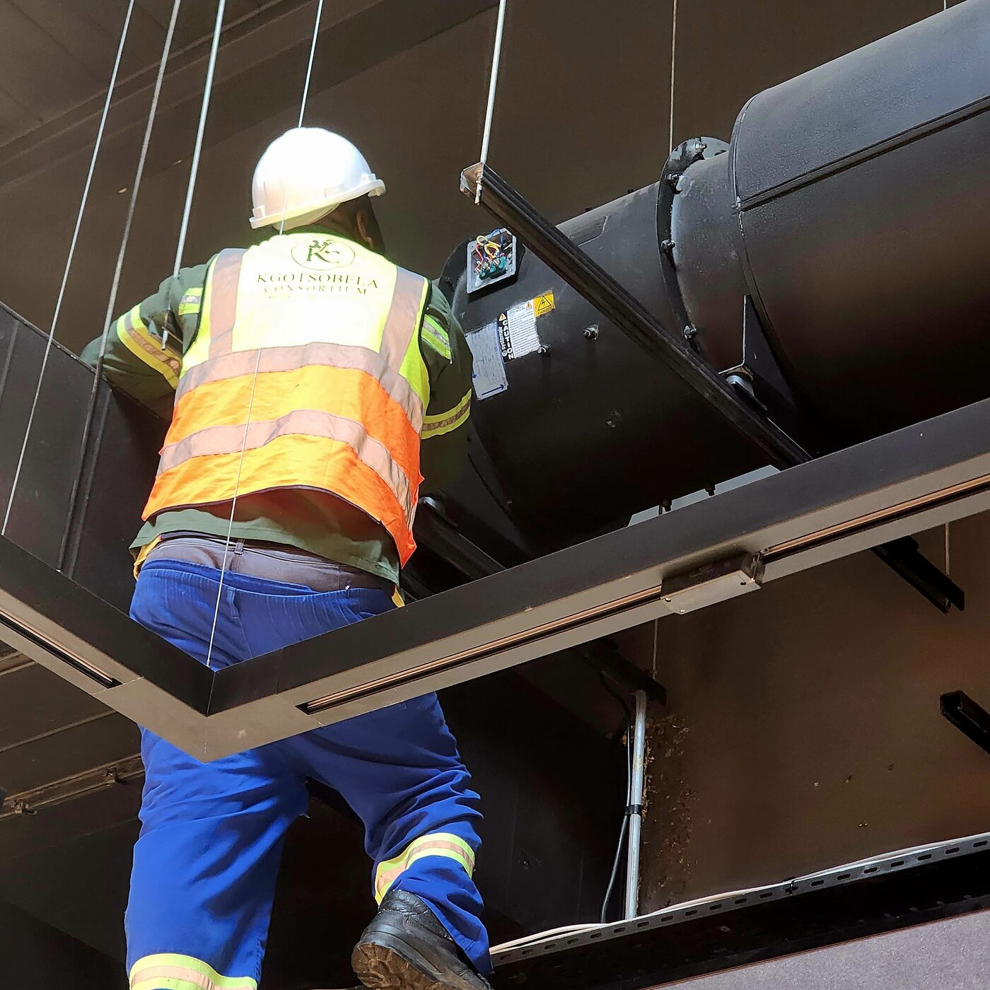 Technician routing cabling on rooftop plant equipment