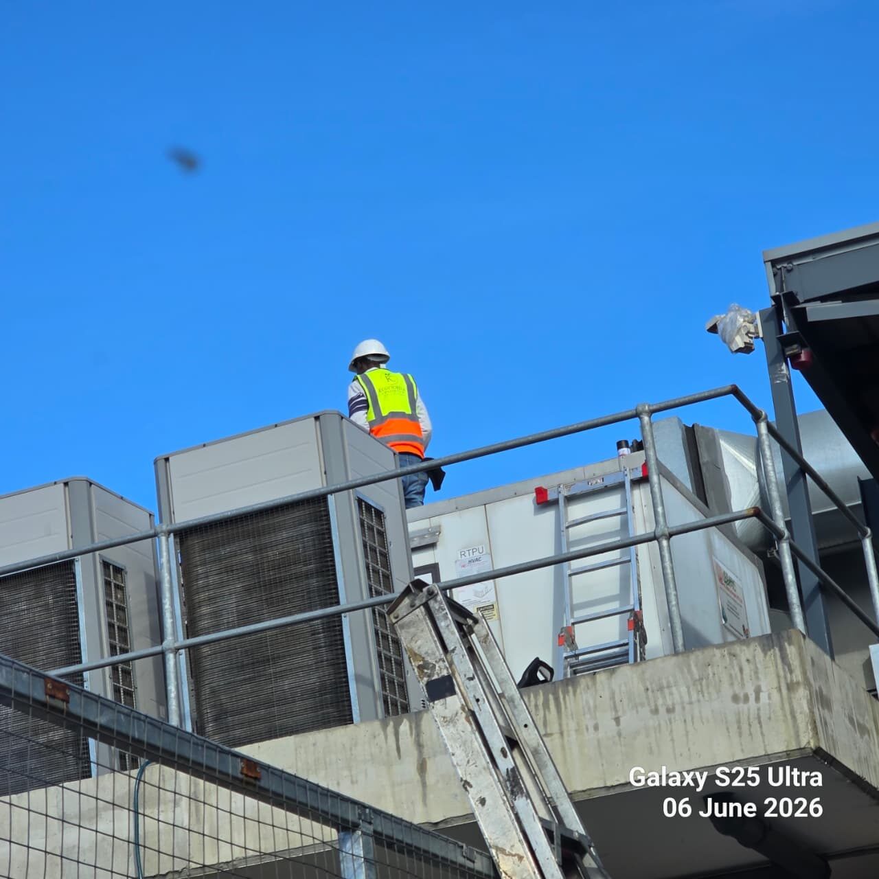 Technician inspecting rooftop condenser units